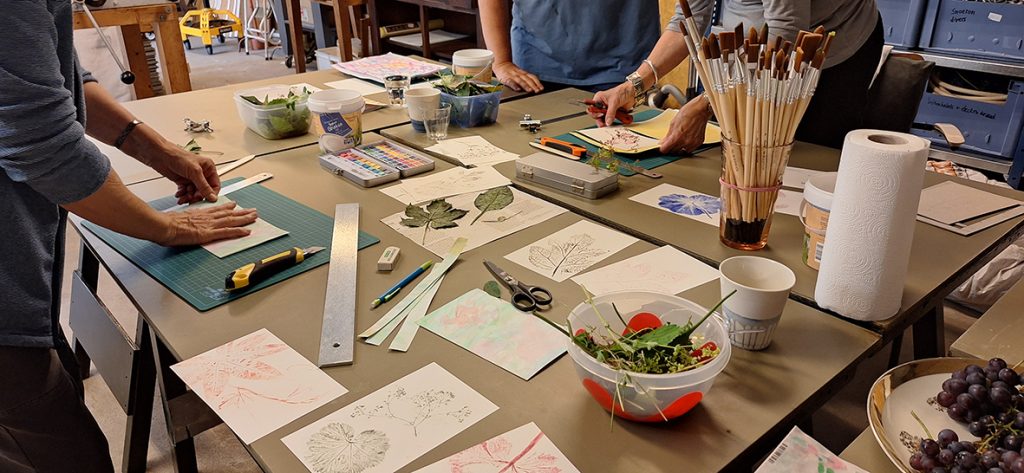 Deelnemers aan het werk aan de grote tafel in het atelier.